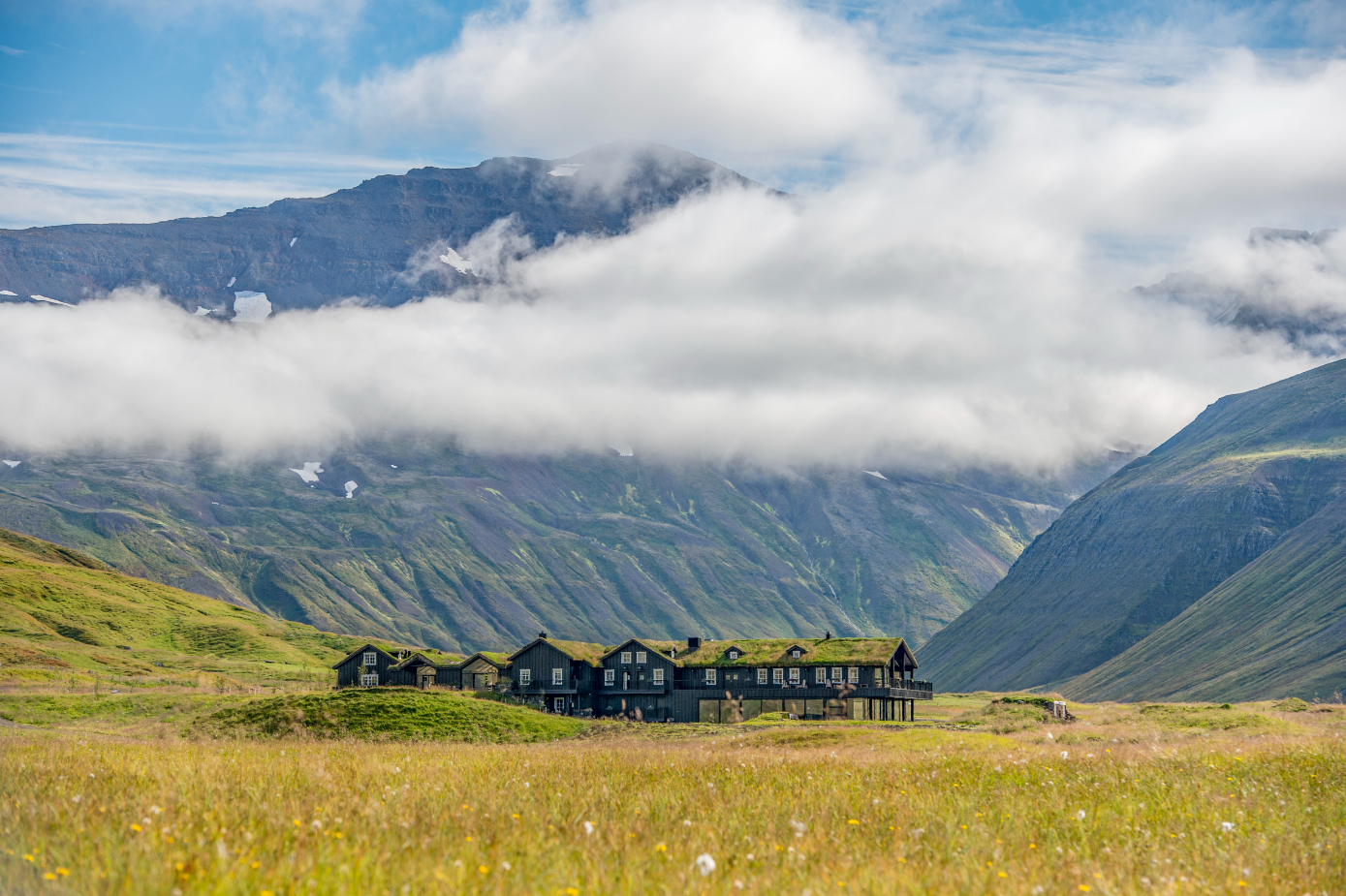 Deplar Farm luxury lodge nestled in a remote green valley on Iceland's Troll Peninsula with mountain peaks rising on all sides
